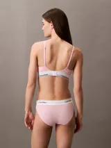 Conjunto Calvin Klein Modern Cotton color rosa pálido, compuesto por un corpiño triángulo con copas sin relleno y una bombacha tipo bikini. Ambos con banda elástica blanca con logo de la marca.