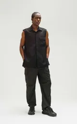 Camisa negra sin mangas de calce oversize con doble bolsillo y detalle de remaches en el frente, confeccionada en tejido twill de alta calidad.