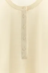 Camiseta negra de manga larga con cuello redondo y cierre frontal con botones.