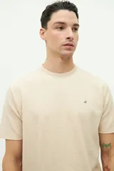 Remera color beige con textura, de manga corta, cuello redondo y logo estampado en el pecho.