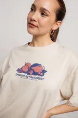 Remera color crema de algodón con estampado de frutas y texto en azul.