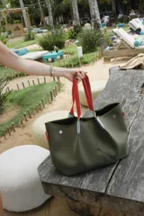 Bolso negro tipo tote de neopreno con bolsillo interno de red, sobre haciendo juego y gancho para sujetarlo.