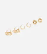 Set de tres pares de aros dorados: un par de argollas con apliques de flores y perlas, un par de argollas lisas y un par de aros con forma de flor con una perla en el centro.