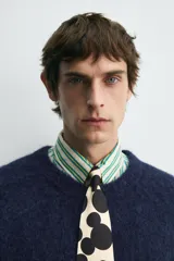 Cárdigan azul marino de manga corta tejido en hilatura con lana y alpaca, de textura suave. Tiene cuello redondo, rib en los bordes y cierre frontal con botones. Edición especial Harry Lambert for Zara x Disney.