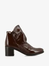 Botín de cuero acharolado color marrón oscuro, con taco cuadrado y diseño moderno.