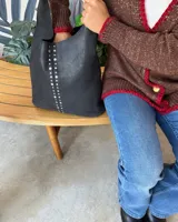 Bolso de hombro negro con tachas plateadas en los bordes.