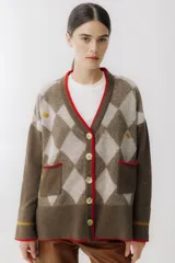 Cárdigan color beige con patrón de rombos en tonos marrones y detalles en rojo. Tiene cuello en V, cierre frontal con botones, bolsillos delanteros y puños acanalados.