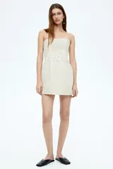Vestido corto strapless color beige, confeccionado en mezcla de lino y viscosa, con bordado de nudo francés tono sobre tono en la parte superior.