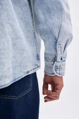 Sobrecamisa de jean de hombre, color azul claro con efecto acid wash. Posee cuello camisero, cierre frontal de botones y dos bolsillos con tapa en el pecho.