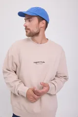 Buzo color crema de manga larga y cuello redondo, con logo 'Originals Studio Brought to you by Jack&Jones Designed in Copenhagen' estampado en el pecho.