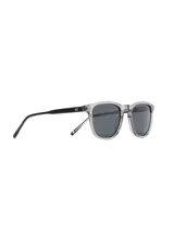 Lentes de sol estilo retro con montura clara y lentes oscuros.