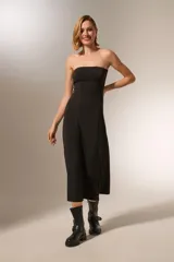 Vestido negro sin mangas, de corte ajustado al cuerpo y largo midi, con escote strapless.