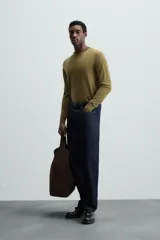 Jersey negro de lana con acabado mercerizado, corte relaxed fit, cuello redondo y mangas largas con terminaciones en rib.