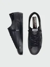 Zapatillas urbanas Golden Goose modelo Super-Star para hombre, confeccionadas en cuero napa color negro. Presentan el icónico parche de estrella en el lateral, inscripción 'GGDB/SSTAR' y suela de goma con efecto desgastado.