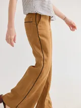Pantalón de lino azul con corte palazzo y vivos a contratono color beige en los laterales.