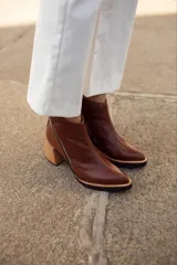 Bota corta de cuero color borgoña con textura de piel de reptil, cierre lateral con cremallera y tacón geométrico de madera clara.