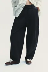 Pantalón cargo negro de corte amplio con cintura ajustable con cordón, bolsillos laterales y bolsillos tipo parche en las piernas.