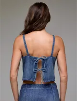 Top corto de denim azul con apliques de strass plateados distribuidos por toda la prenda. Presenta un escote en V y breteles finos, también adornados con strass.