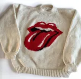 Sweater tejido a mano en lana merino color crudo, con cuello redondo y puños y ruedo acanalados. Presenta un diseño tejido en el frente con el logo de la lengua de los Rolling Stones en rojo y negro.