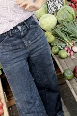 Pantalón jean azul oscuro, de corte wide leg y tiro medio. Presenta detalles de costuras diagonales en la parte superior.