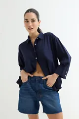 Camisa de manga larga color verde oliva, con cuello clásico y botones frontales blancos. Presenta un calce holgado y tejido de aspecto rústico.