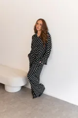 Camisa negra con estampado de lunares blancos, de manga larga y cuello clásico.
