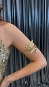 Brazalete dorado para el brazo con diseño de hojas.