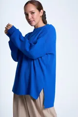 Sweater color beige de tejido de punto acanalado, con cuello redondo y mangas largas. Tiene corte holgado y aberturas laterales en el ruedo.