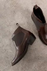 Botín Chelsea de cuero marrón con elástico lateral y tacón bajo.