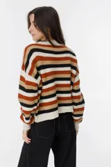 Sweater tejido a mano con diseño geométrico en tonos marrón, beige, negro y blanco.