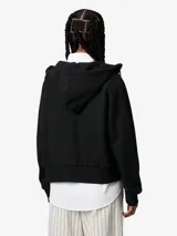 Campera negra con capucha ajustable, cierre frontal con cremallera, bolsillo tipo canguro con remaches metálicos y logo cuadrado en el frente.