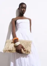 Bolso de mano tipo clutch color beige, tejido en fibra natural con flecos.