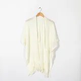 Ruana color crema con diseño calado y flecos en el borde inferior.