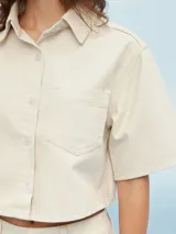 Camisa de manga corta color celeste, con cuello clásico, cierre frontal con botones y bolsillo de parche en el pecho.