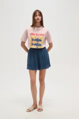 Remera blanca de algodón con cuello redondo y mangas cortas. Estampado frontal con diseño de peces azules sobre fondo a cuadros amarillos y texto "Isola di Capri" y "Amalfi Coast".