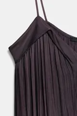 Vestido midi color morado oscuro, con escote en V y tirantes finos. El tejido presenta un acabado satinado y un efecto plisado o arrugado que le da fluidez.