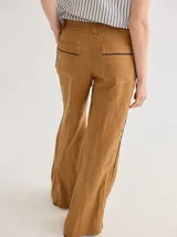 Pantalón de lino color ocre, de corte palazzo con bolsillos traseros y vivos negros a contratono.