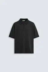 Polo negro de punto con cuello solapa y cierre frontal de cremallera. Manga corta y corte regular fit.