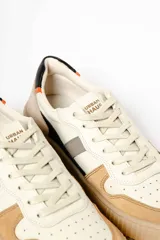 Zapatillas deportivas color beige con detalles en gris, blanco, negro y rojo.