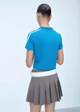 Polo deportivo azul con cuello clásico, corte entallado y mangas cortas con dos rayas blancas en los hombros.