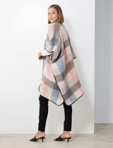 Ruana de tejido soft, color rosa pálido, celeste, gris y beige, con diseño a cuadros. Presenta terminación en zig zag con lana en los bordes y sisa amplia.