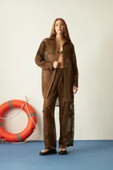 Camisola larga de red marrón, con diseño de tejido a cuadros y apliques florales bordados en relieve por toda la prenda. Presenta cuello camisero y botones frontales.