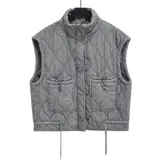 Chaleco acolchado gris con cuello alto, cierre frontal con cremallera, dos bolsillos delanteros con solapa y cordones ajustables en el bajo.