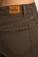 Pantalón jean marrón de corte flare, tiro medio y terminación desflecada.