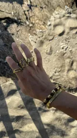 Brazalete rígido dorado con textura irregular.