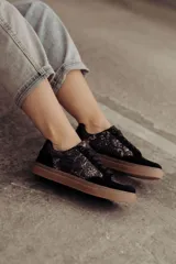 Zapatillas bajas negras con estampado de piel de serpiente metalizada y suela color caramelo.