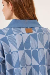 Cardigan azul con estampado de corazones geométricos en dos tonos de azul, con cuello polo y cierre frontal con botones.