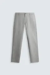 Pantalón gris de corte slim fit, confeccionado en tejido elástico. Cuenta con cintura elástica, bolsillos frontales y traseros de ojal. Cierre frontal con cremallera y botón.