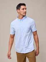 Camisa celeste de manga corta con cuello abotonado y bolsillo en el pecho.
