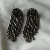 Par de caravanas colgantes con base semicircular y flecos de cuentas facetadas color gris plomo.